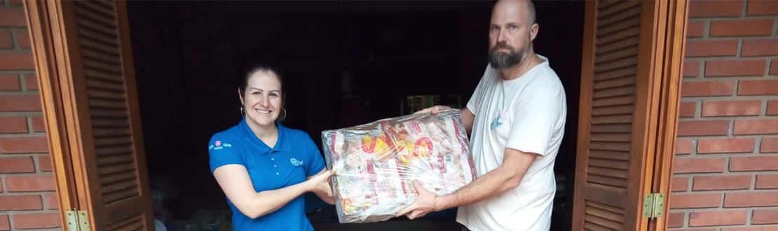 Foto de uma colaborada da BRF entregando uma caixa de papelão com proteínas. A frente deles, há mais caixas no chão.