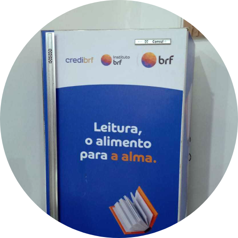 Foto de uma geladeira antiga. Em sua porta, há um adesivo com os logos da CrediBRF, Instituto BRF e BRF, texto “Leitura, o alimento para a alma” e a ilustração de um livro aberto.