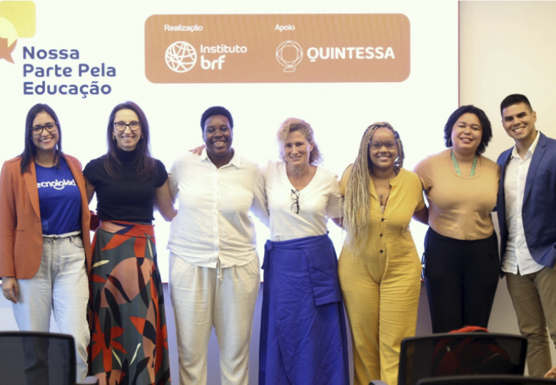 Foto das pessoas representantes das startups, em pé, em frente a um painel com o logo do programa Nossa Parte Pela Educação.